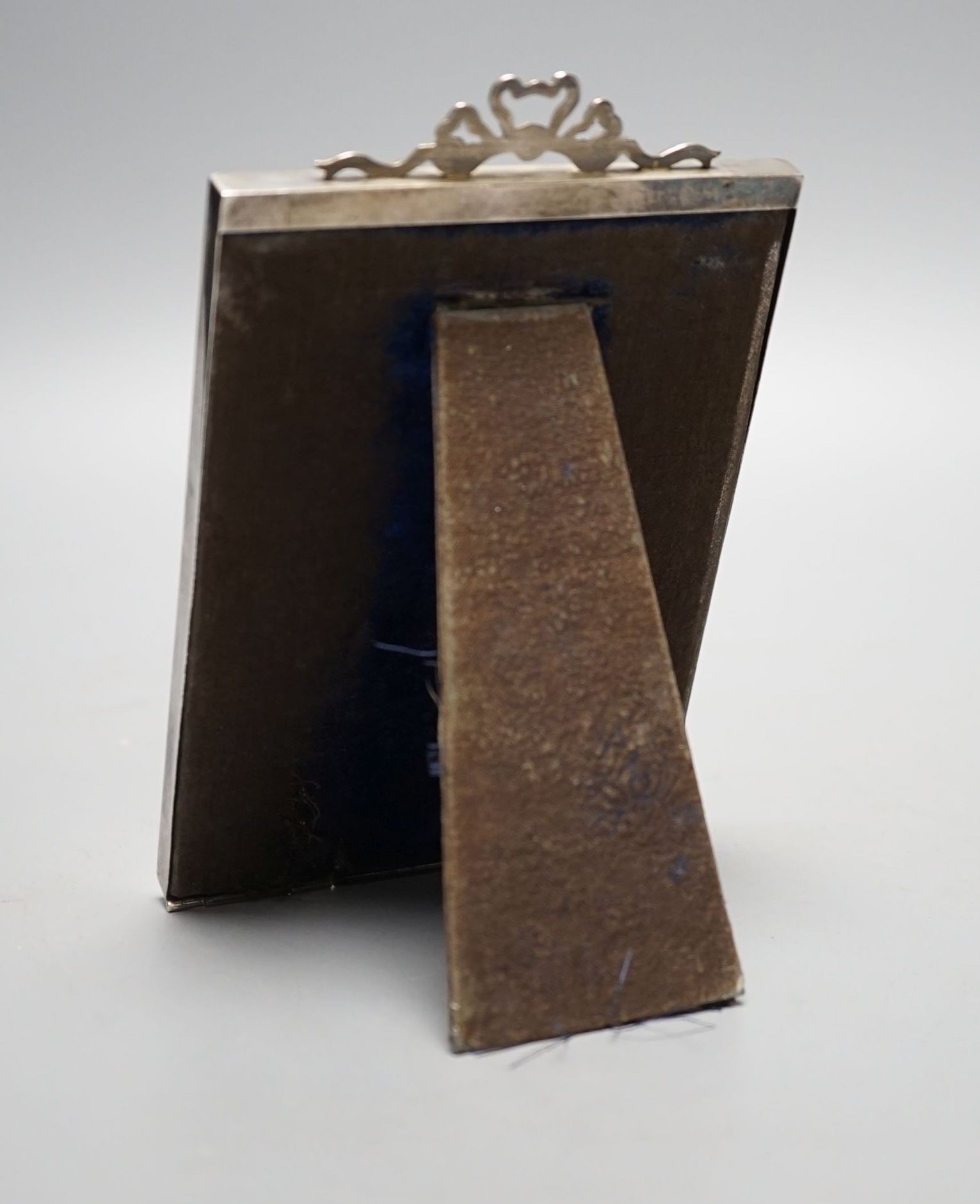 An Edwardian silver mounted photograph frame, with ribbon bow crest, Birmingham, 1902, overall 15.8cm.